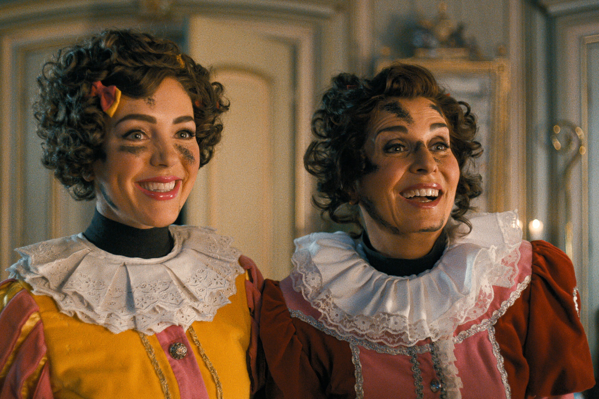 Twee personages uit de film lachen vrolijk binnenshuis, geschminkt met Pietenmake-up