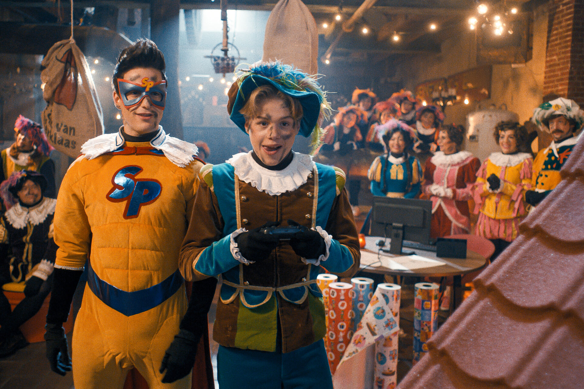 Superpiet en Pietje Fernando staan met een afstandsbediening tussen pakjes en cadeauverpakkingen