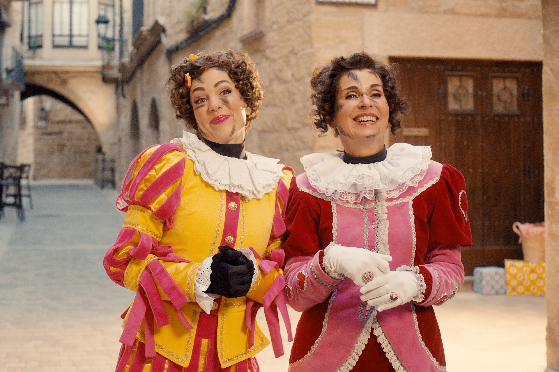 Twee Pieten in feestelijke kostuums lachen samen op het dorpsplein